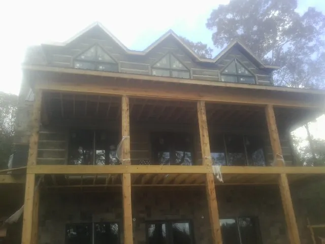 Dormers and porch framing on a large log home under construction — Roof Coating work by our crew in Middletown